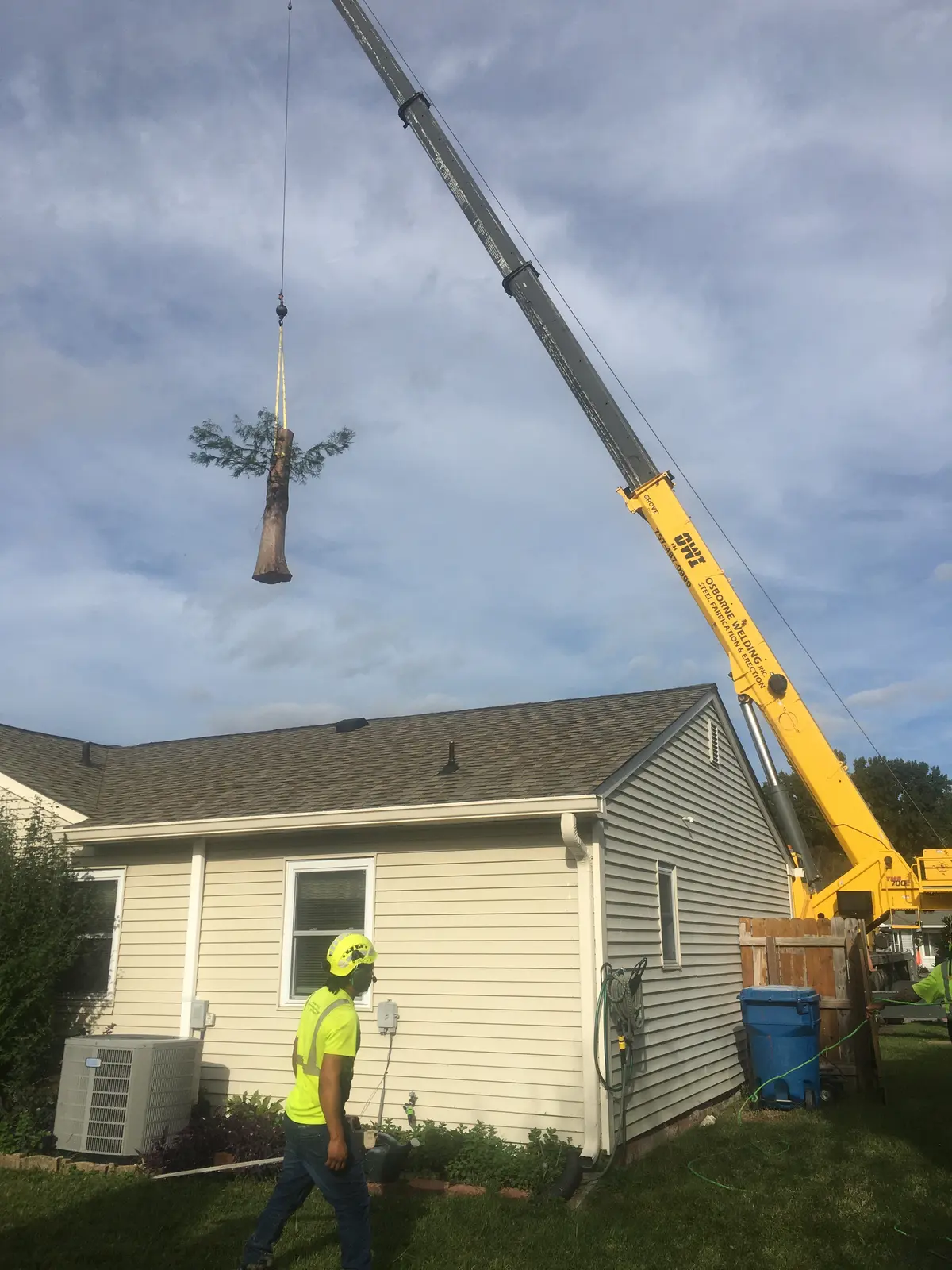 Crane lifting a storm-damaged tree section off a house in Virginia Beach